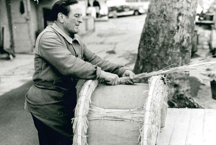 Jean Ros fabricant un bât : habillage du bât avec de la paille